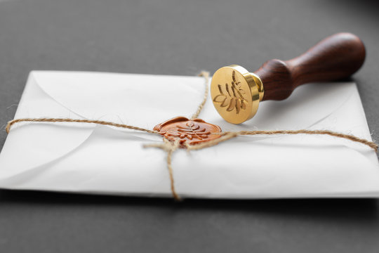 Notary public wax stamper. White envelope with brown wax seal, golden stamp. Responsive design mockup, flat lay. Still life with postal accessories.