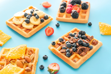 Tasty waffles with fruits and berries on color background