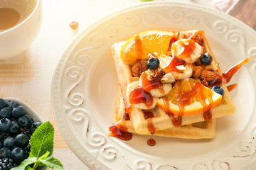 Plate with tasty waffles, fruits and berries on table, closeup