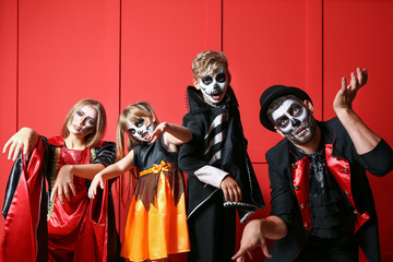 Family in Halloween costumes on color background