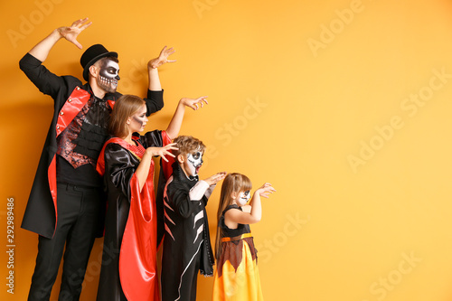 Family in Halloween costumes on color background