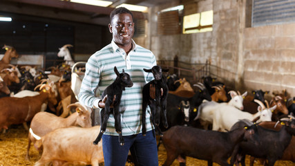 African American owner of goat farm with little goats