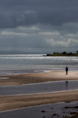 Fototapeta na wymiar beach and man in sunlight at whiting bay on arran