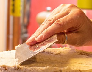 A baker’s hand smoothing a butter cream crumb coat onto a birthday cake