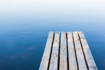 Fototapeta premium Holzsteg mit Wasserspeigelung. Beruhigendes Hintergrundbild. Wooden pier with water reflection. Relaxing background picture.