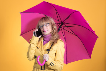 adult woman with umbrella and mobile phone isolated on color background