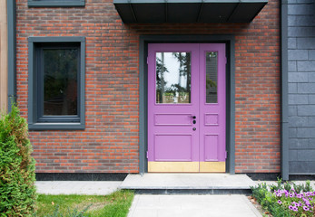 Fototapeta na wymiar Original lilac front door and window on the background of decorative brickwork