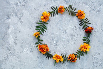 Round frame for text made of fresh flowers of orange color. Composition isolated on gray background. Top view, flat lay. Space for text.