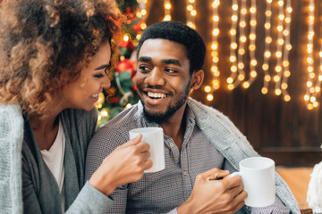 Young couple drinking coffee at Christmas tree - Powered by Adobe