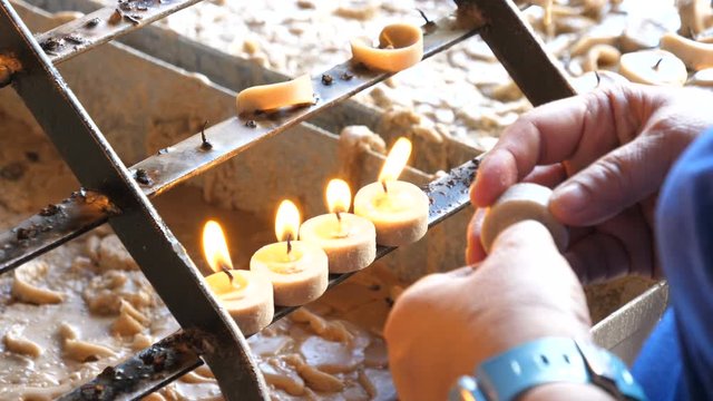 Asian women hand places candle on plateau in church