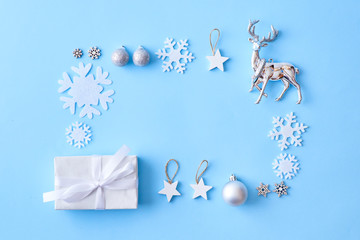 Flat lay christmas frame with snowflakes, balls and gift box on a blue background