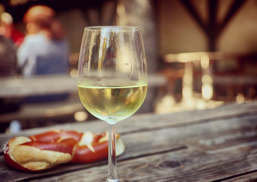 Glass Of White Wine And Pretzel At Beer Garden In Bavaria