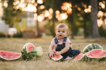 Portrait of beautiful baby girl eating watermelon. Child eating watermelon in the garden. Adorable little girl playing in the garden biting a slice of watermelon