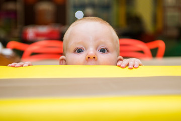 Small kid peeking over armchair. Child looking over armchair