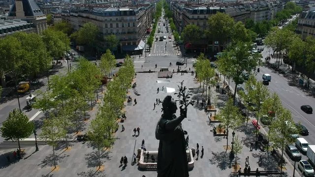 Fly over Place de la Republique bronze liberty statue people city street Paris France drone aerial