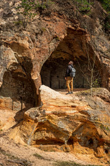 Sandstone Caves in Ligatne with a men standind near by, Latvia. Caves with  old wooden doors.