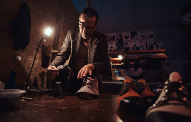 Elderly person is serving boot service at his own personal workshop.