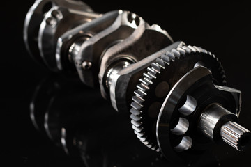 high performance factory racing crankshaft. set on a black reflective background with different lighting.