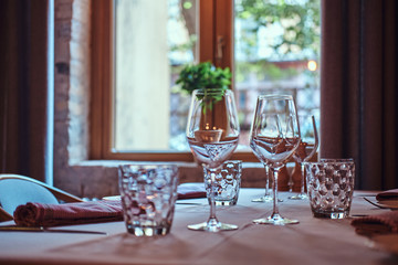 There are glasses for wine and water on the table with white cloth are ready for dining.