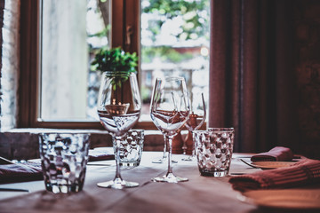 There are glasses for wine and water on the table with white cloth are ready for dining.