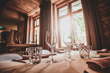 There are glasses for wine and water on the table with white cloth are ready for dining.