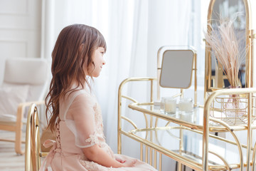 Cute little girl near oval mirror at dressing table