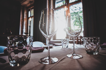 There are glasses for wine and water on the table with white cloth are ready for dining.