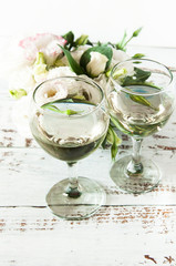 Glasses with wine on a white rustic wooden background with a bouquet of flowers. Wedding table greeting card. Wedding invitation light background.