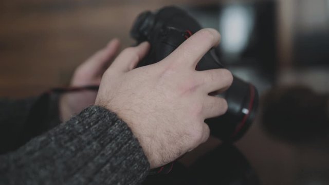 Photoghrapher holds and use a camera indoor