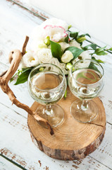 Glasses with wine on a white rustic wooden background with a bouquet of flowers. Wedding table greeting card. Wedding invitation light background.