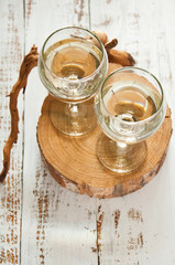 Glasses with wine on a white rustic wooden background with a bouquet of flowers. Wedding table greeting card. Wedding invitation light background.