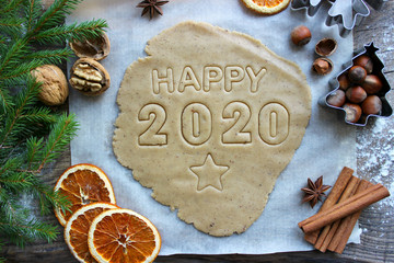 Fototapeta na wymiar Text 2020. Concept of the new year 2020. Christmas pastries. Homemade cakes or cookies for the new year and Christmas.Spices, nuts, dried oranges, fir branches, wooden background. Rustic style. New ye