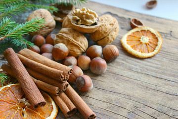 Christmas decor. Christmas spices. Cinnamon sticks, anise stars, walnuts, hazelnuts, dried orange on an old wooden background, copy space.