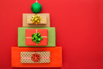 Christmas composition. Christmas gift boxes laid out in the shape of a Christmas tree on red background. Flat lay, top view, copy space.