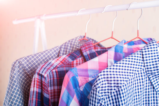 Colorful checkered shirts on hangers.