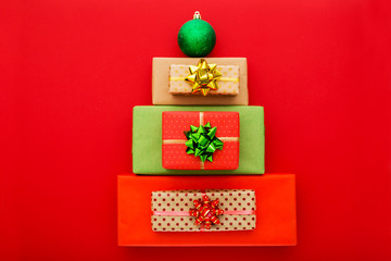 Christmas composition. Christmas gift boxes laid out in the shape of a Christmas tree on red background. Flat lay, top view, copy space.