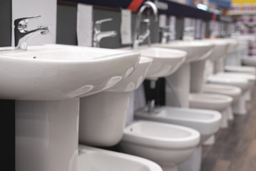 New white sink and toilet bowl in a store abstract background.