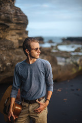 Fototapeta premium Romantic young man with a guitar on the beach
