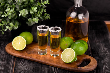 Mexican Gold Tequila with lime and salt on black background with copyspace.