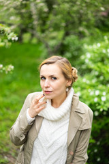 Beautiful blond woman posing outdoors at the blur spring park of violet and white lilac background