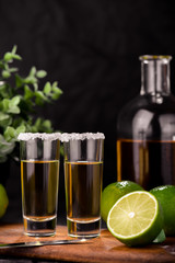 Mexican Gold Tequila with lime and salt on black background with copyspace.
