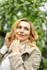 Beautiful blond woman posing outdoors at the blur spring park of violet and white lilac background