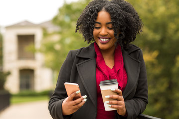 African American Woman texting and drinking coffee.