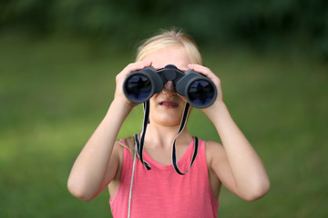 Petite fille regardant à travers des jumelles en plein air