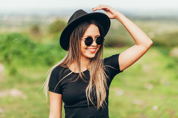 Portrait of young woman wearing fedora hat and sunglasses - obrazy, fototapety, plakaty