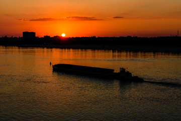 Long heavy barge on a Dnieper river near city Kremenchug at sunset