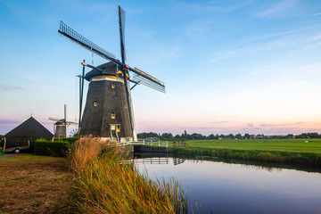 Naklejka premium windmill landscape photo with canal and bushes under open blue sky