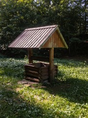 Old wooden well on green grass