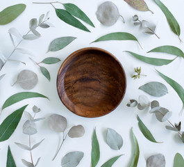 empty plate, eucalyptus leaf border blank space, green leaves and dried rosebuds, flat lay border on white background, bright flatlay, composition, frame, creative concept, mockup, blank, copyspace
