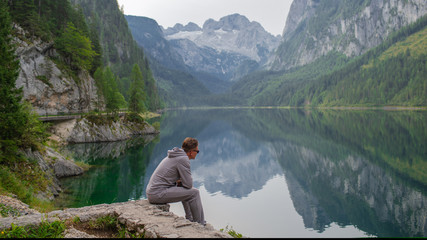 Young sports guy enjoys the beauty on the lake in the mountains